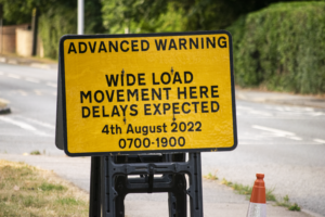 Advanced Warning Traffic Sign That Reads "WIDE LOAD MOVEMENT HERE DELAYS EXPECTED"