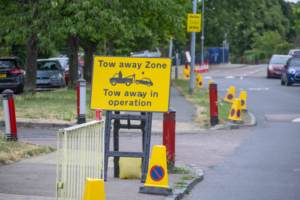 Parking Restriction Cones Along Road Edge, With Sign Adjacenet That Reads "TOW AWAY ZONE"